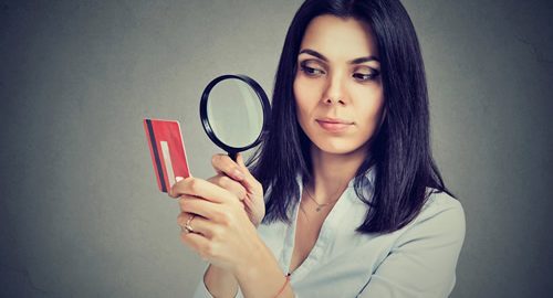 Woman looking through a magnifying glass at a credit card