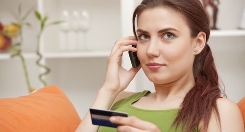 Young woman on the phone and holding a credit card